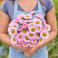 Person holding a bouquet of china aster matsumoto pink flowers with a blurred green background