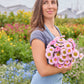 Person holding a bouquet of china aster matsumoto pink flowers with a blurred green background