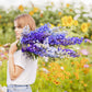 Person holding a bouquet of delphinium pacific mix flowers in a garden setting